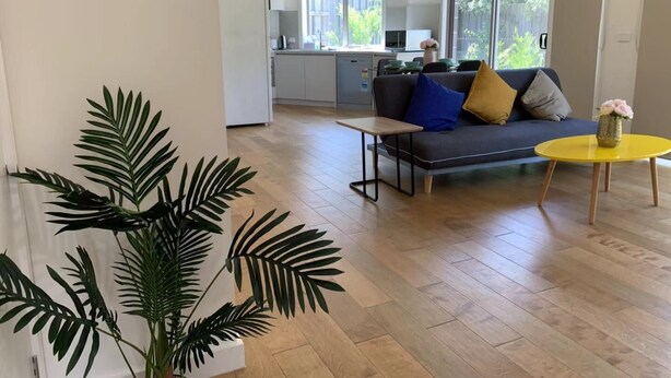 A modern living room with a sofa, a coffee table, and a large window. - Delicate Bundoora townhouse 10 (Bundoora)