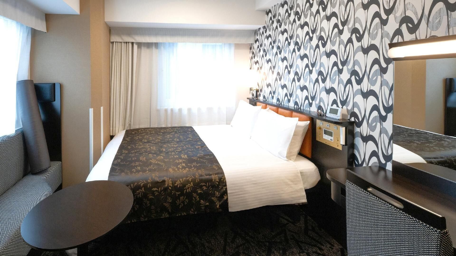 Una habitación de hotel con una cama, un escritorio, una silla y una mesita.