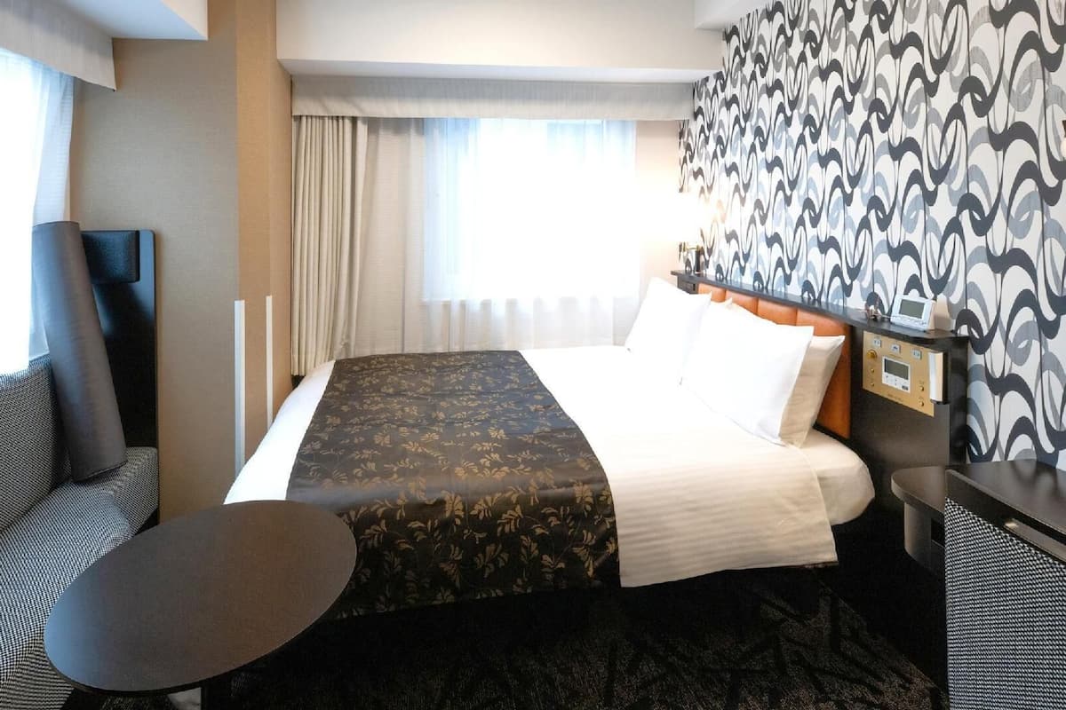 Una habitación de hotel con una cama, un escritorio, una silla y una mesita.