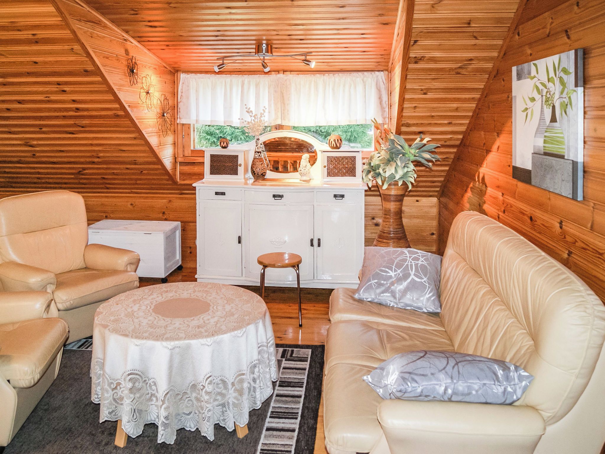 Ein gemütliches Blockhaus-Interieur mit Essbereich, weißen Schränken, einer Couch und einem Tisch.