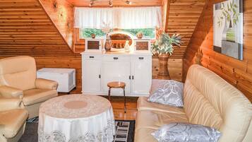 Ein gemütliches Blockhaus-Interieur mit Essbereich, weißen Schränken, einer Couch und einem Tisch.