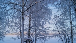 A snow-covered outdoor area with a wooden structure, possibly a gazebo, surrounded by trees. - Kesäranta by Interhome (Enonkoski)