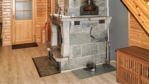 A stone fireplace with a chimney, a wooden door with frosted glass panels, and a wooden staircase. - Kesäranta by Interhome (Enonkoski)