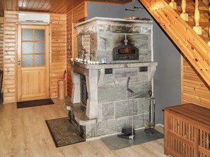 A stone fireplace with a stone mantel, a wooden door with frosted glass panels, and a wooden staircase. - Kesäranta by Interhome (Enonkoski)