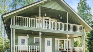 A two-story wooden house with a balcony, a front porch, and a small table. - Kesäranta by Interhome (Enonkoski)