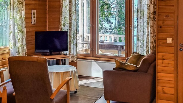A cozy cabin-style room with a television, a sofa, and a dining table. - Kesäranta by Interhome (Enonkoski)