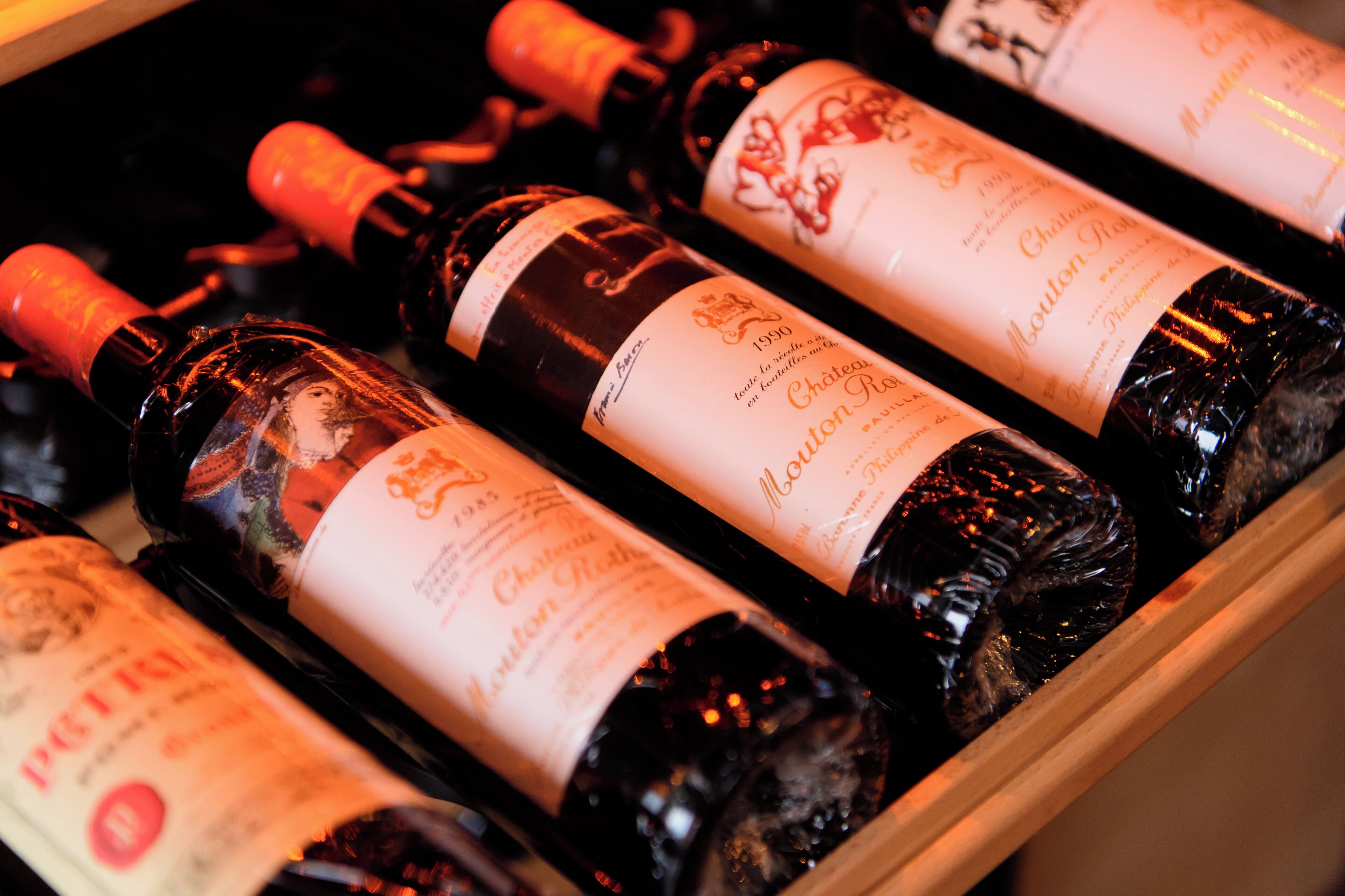 A wooden wine rack holding several bottles of Châteauneuf Rothschild wine.