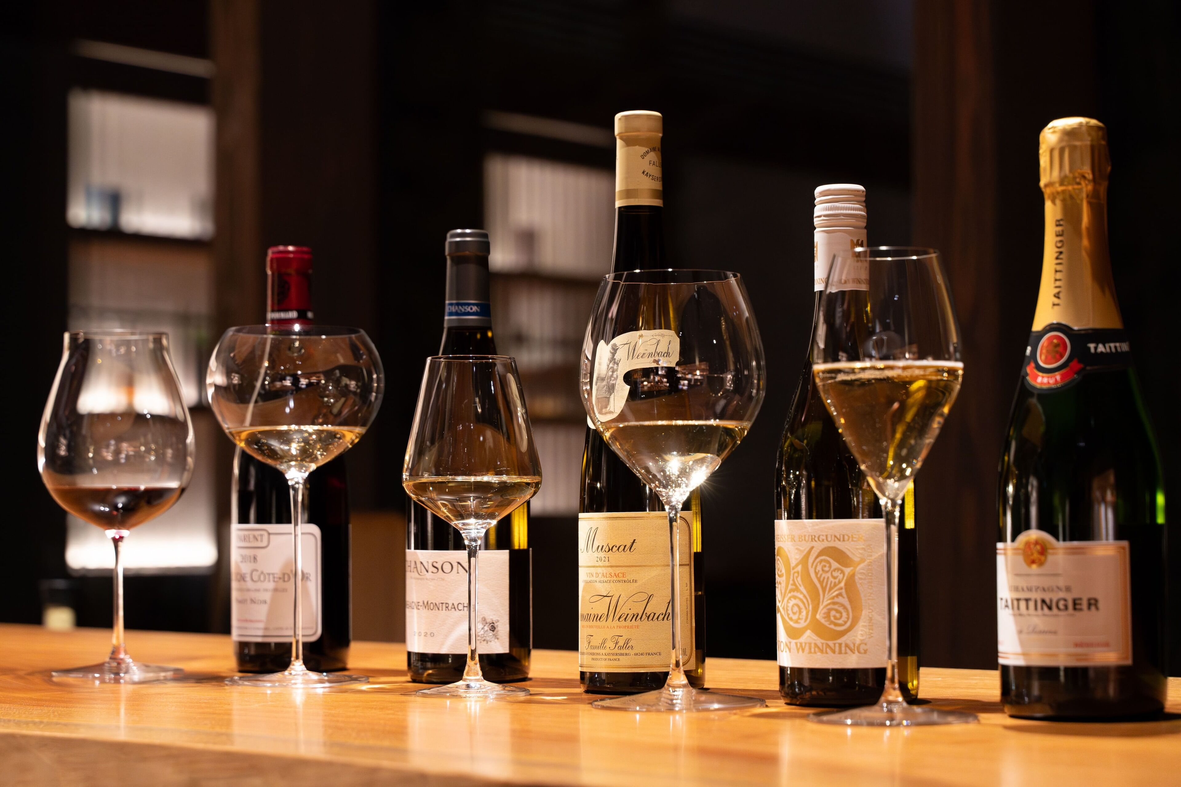 A selection of wine bottles and glasses on a wooden table.
