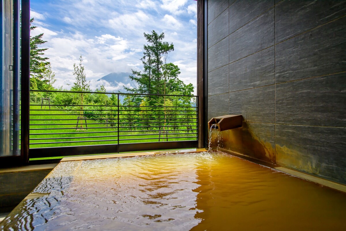 A hot tub with a view of a green landscape and a mountain in the background.