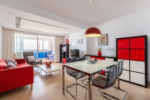 Un salon moderne avec un canapé rouge, une table à manger en verre et un meuble rouge.