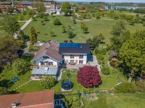 A two-story house with a large front yard, solar panels, and a trampoline. - Apartment "Julia" with Lake View, Mountain View, Wi-Fi, Garden & Terrace (Taching am See)