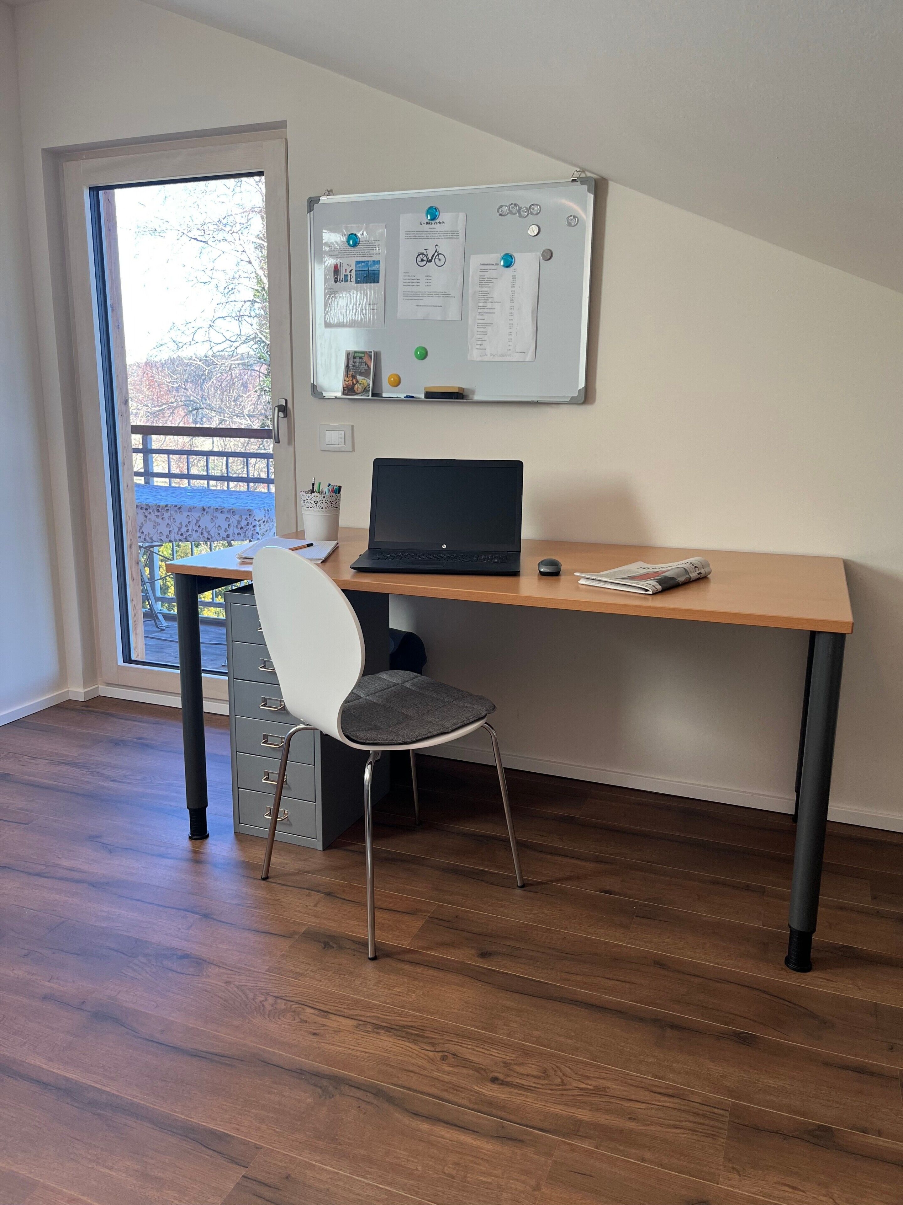 A workspace with a laptop, chair, and whiteboard.