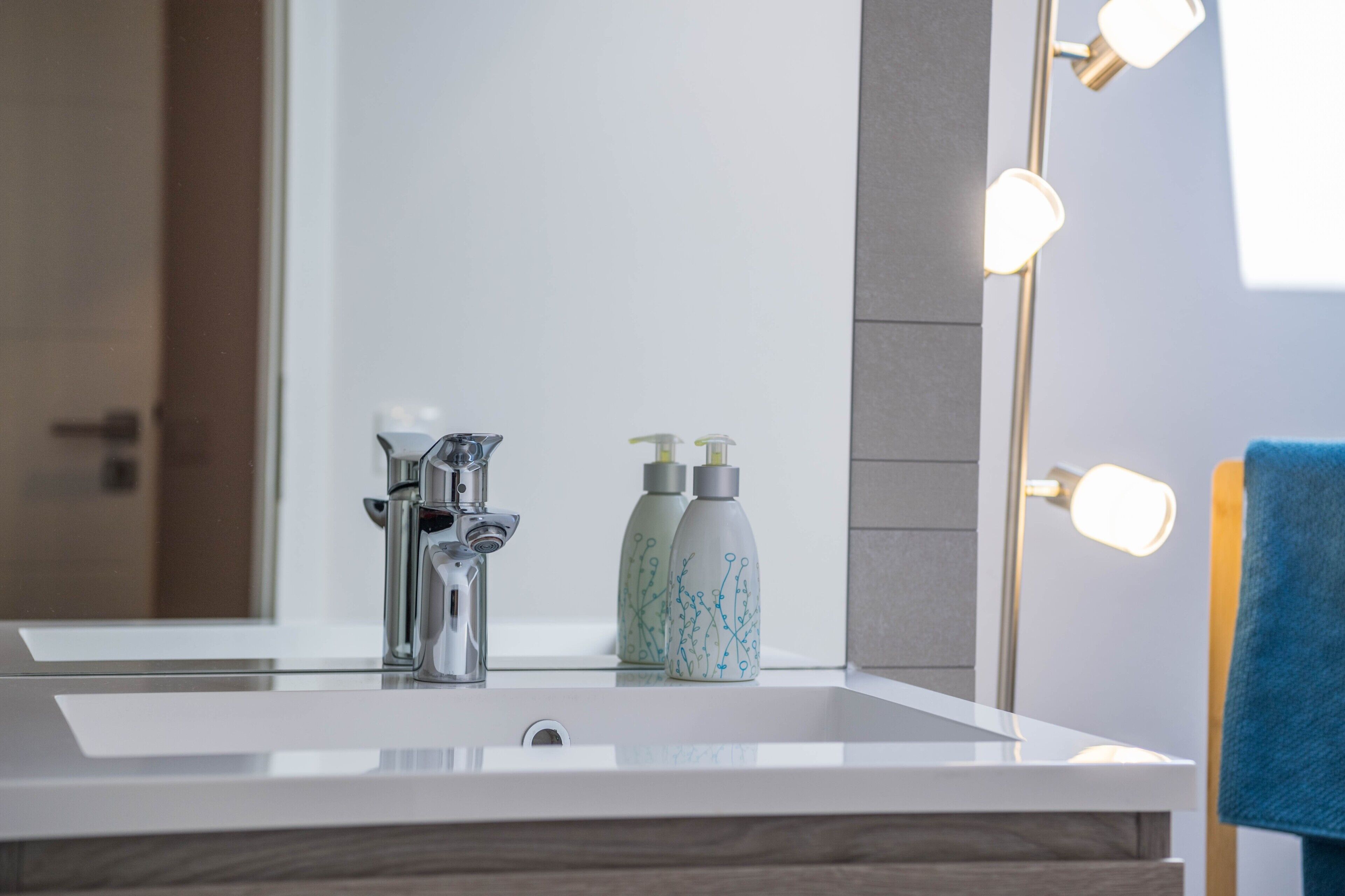 Une salle de bain avec un lavabo moderne, un miroir et deux flacons de savon liquide.