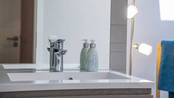 Une salle de bain avec un lavabo moderne, un miroir et deux flacons de savon liquide.