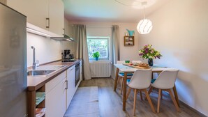 Une cuisine moderne avec un coin repas, une fenêtre avec des rideaux et une table avec des chaises.