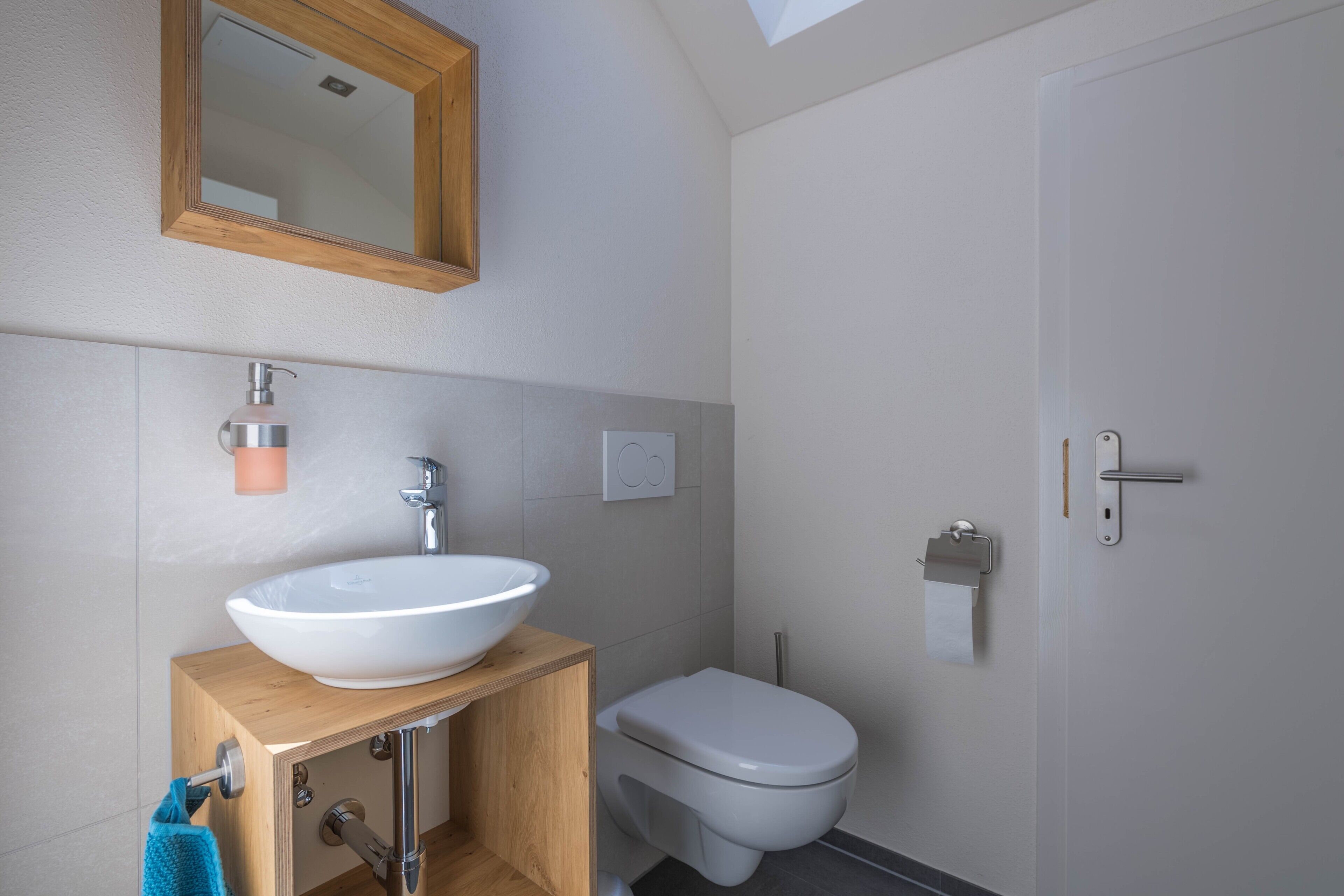 A bathroom with a wooden vanity, white sink, and toilet.