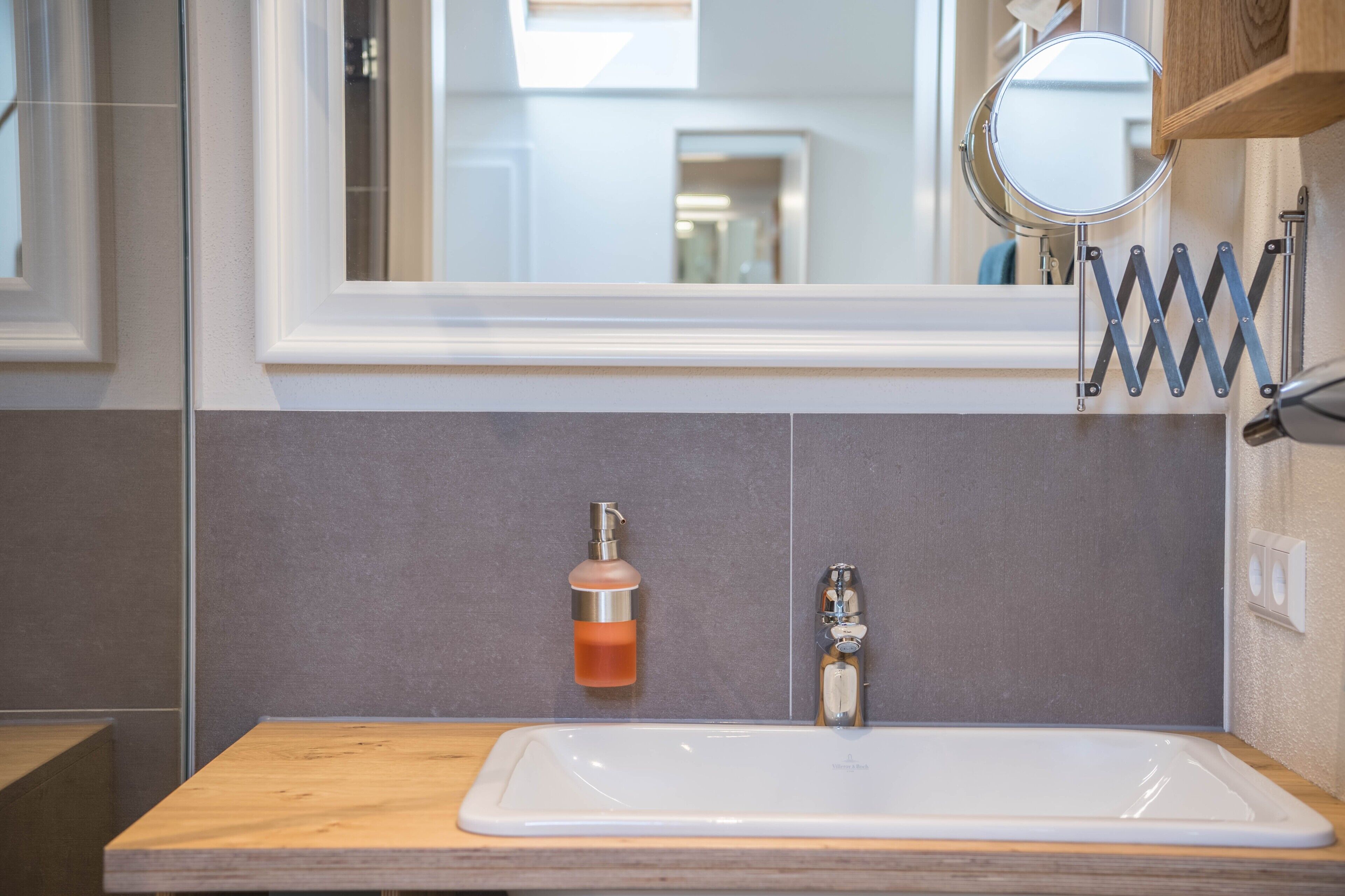 Une salle de bain avec un lavabo blanc, un miroir et un distributeur de savon.