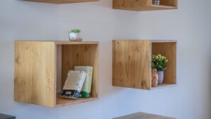 Houten wandplanken met boeken, een glazen vaas en een klein plantje.