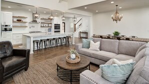 A spacious living area with a sofa, coffee table, and a kitchen in the background.