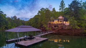A lakeside cabin with a dock and a covered seating area.