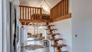 A modern interior with a wooden staircase, a glass door leading outside, and a leather rug on the floor. - Modern House "El Loft" with Sea and Mountain View, Wi-Fi & Terrace (Famara)