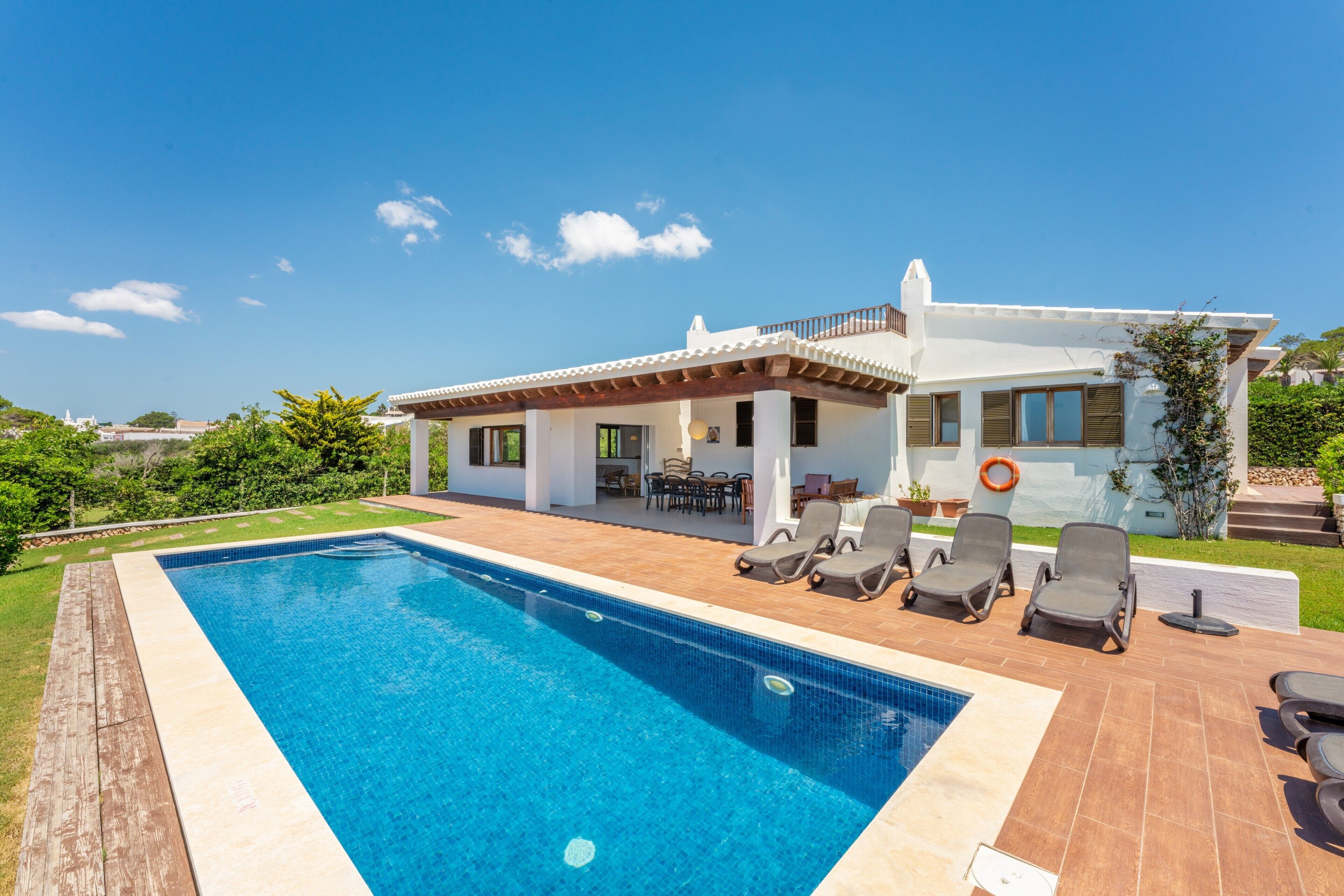 A modern house with a swimming pool, outdoor furniture, and a view of the surrounding landscape.