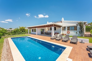 A modern house with a swimming pool, outdoor furniture, and a view of the surrounding landscape.