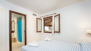 Een slaapkamer met een bed, een badkamer met een douche en een raam met gordijnen.