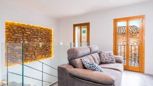 Ein modernes Wohnzimmer mit einer Couch, einer Glasstiege, einer Steinwand und einer Holztür.