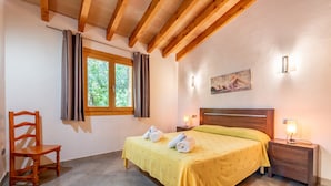 A bedroom with a bed, wooden chair, bedside table, nightstand, window, and a painting on the wall. - Mediterranean Finca "Es Puch" with Mountain view, Balcony, Garden, Terrace & Pool (BUGER)