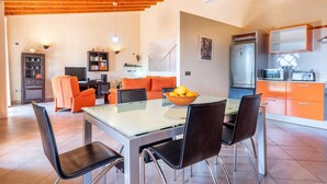 A modern kitchen with a refrigerator, microwave, and orange cabinets. - Mediterranean Finca "Es Puch" with Mountain view, Balcony, Garden, Terrace & Pool (BUGER)
