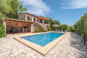 A stone pool with a stone deck, outdoor furniture, and a two-story house with a balcony. - Mediterranean Finca "Es Puch" with Mountain view, Balcony, Garden, Terrace & Pool (BUGER)