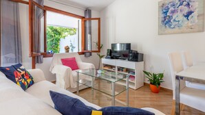 Ein modernes Wohnzimmer mit einem Glastisch, einem weißen Sofa und einer TV-Konsole mit Lautsprechern.
