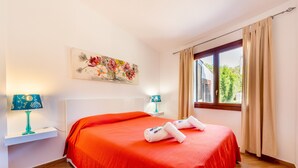 Ein Hotelzimmer mit einem großen Bett, zwei Nachttischlampen, einem fenster mit Vorhängen und einem Blumenbild an der Wand.