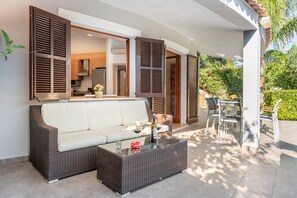 An outdoor living area with a sofa, a glass-top coffee table, and a dining table with chairs. - Charming Holiday Home "Casa Pequeña Crestatx" with Wi-Fi, Garden, Terraces & Pool (CRESTATX)