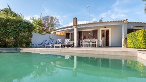 Ein Pool mit Liegestühlen und einer überdachten Terrasse.