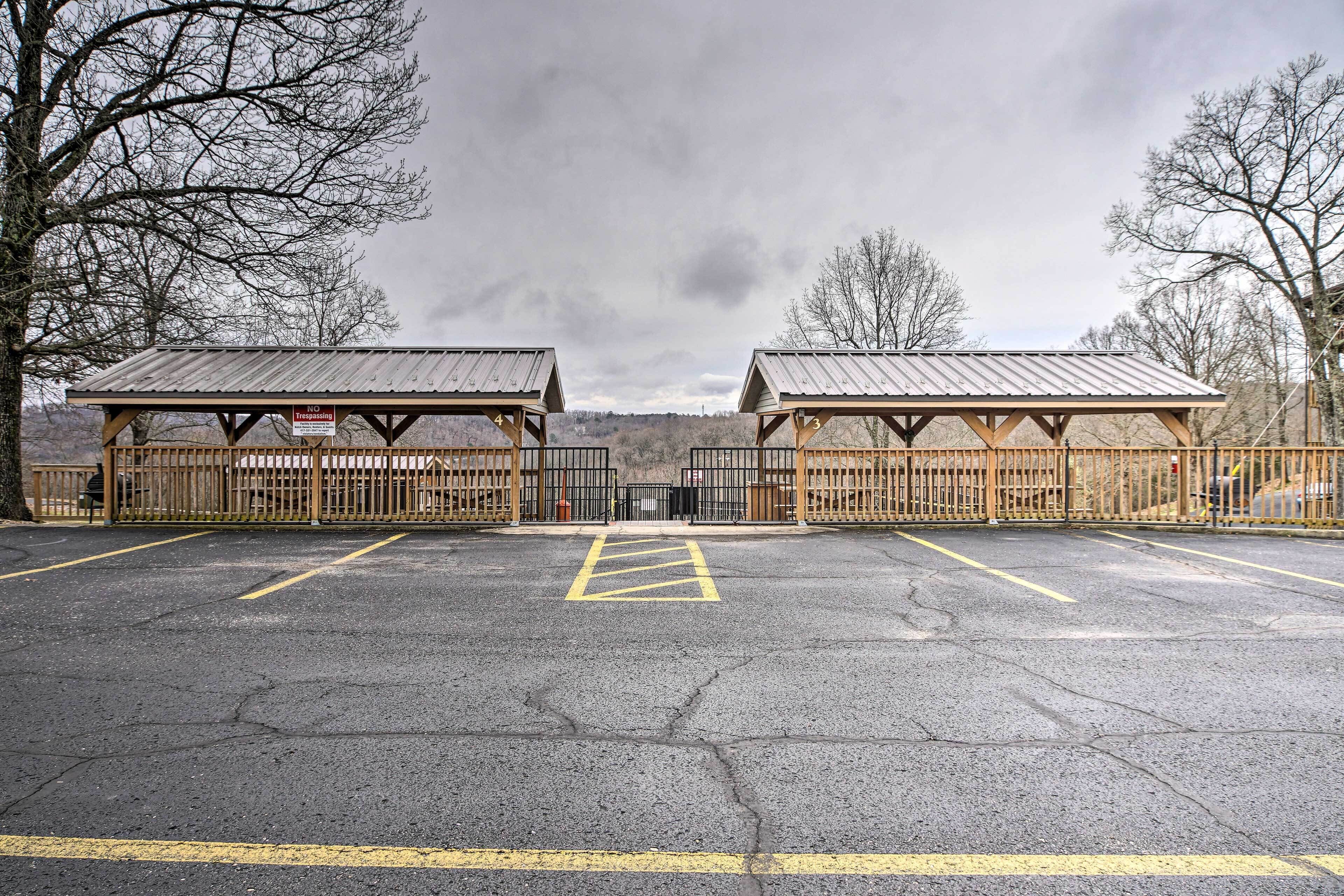 A parking lot with two covered shelters and a fence.