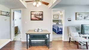 A room with a ceiling fan, a dining table with benches, a bed with a blue bedspread, a chair with a patterned cushion, and a television. - 2 Mi to Silver Dollar City: Reed Springs Condo (Reeds Spring)