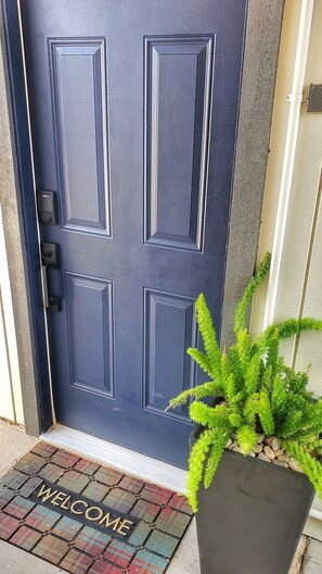 Enter a warm and inviting space with a traditional door featuring a modern electronic lock and a touch of greenery.