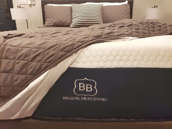 Restful retreat with a neatly made bed featuring a quilted headboard and embroidered details.