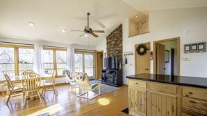 Uma cozinha ampla com armários de madeira, parede com detalhes em pedra e um espaço de refeições com cadeiras e mesa de madeira.