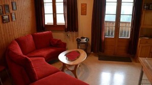 A living room with a red sofa, a small round table, and a radiator. - Adlerhorst by Interhome (Adelboden)