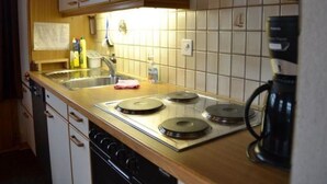A kitchen with a stove, sink, and coffee maker. - Adlerhorst by Interhome (Adelboden)