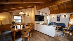 Een houten interieur met een eethoek, een bank en een aan de muur bevestigde televisie.