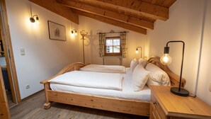 Een houten bed met twee kussens en een nachtkastje met een lamp.
