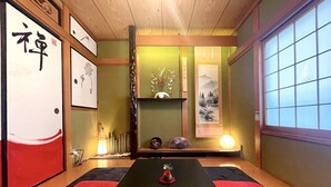 Perinteinen japanilainen huone, jossa on tatamimatot, matala pöytä, kalligrafia ja taideteoksia seinillä.