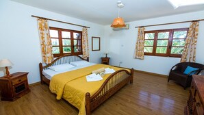 A bedroom with a wooden bed, two bedside tables, a nightstand, a chair, and a window with curtains. - Charming Villa, Private Pool, Hot Tub, Sea Views close to the Pretty Fishing Harbour at Pomos! (Pomos)