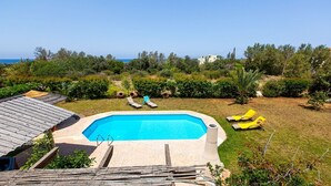 A swimming pool with a view of the sea, surrounded by greenery and a few lounge chairs. - Charming Villa, Private Pool, Hot Tub, Sea Views close to the Pretty Fishing Harbour at Pomos! (Pomos)