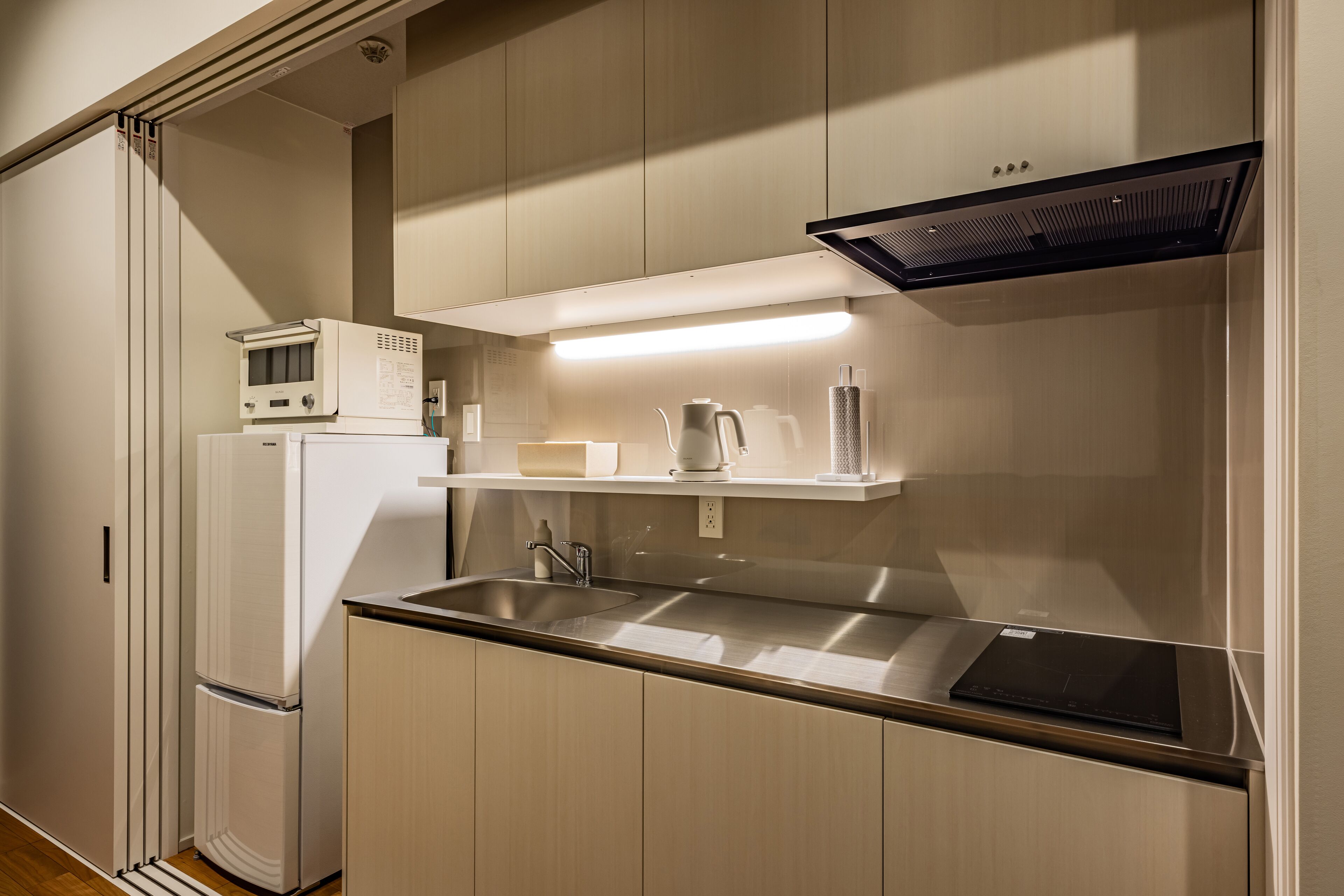 A modern kitchen with a built-in microwave, a kettle, and a sink.
