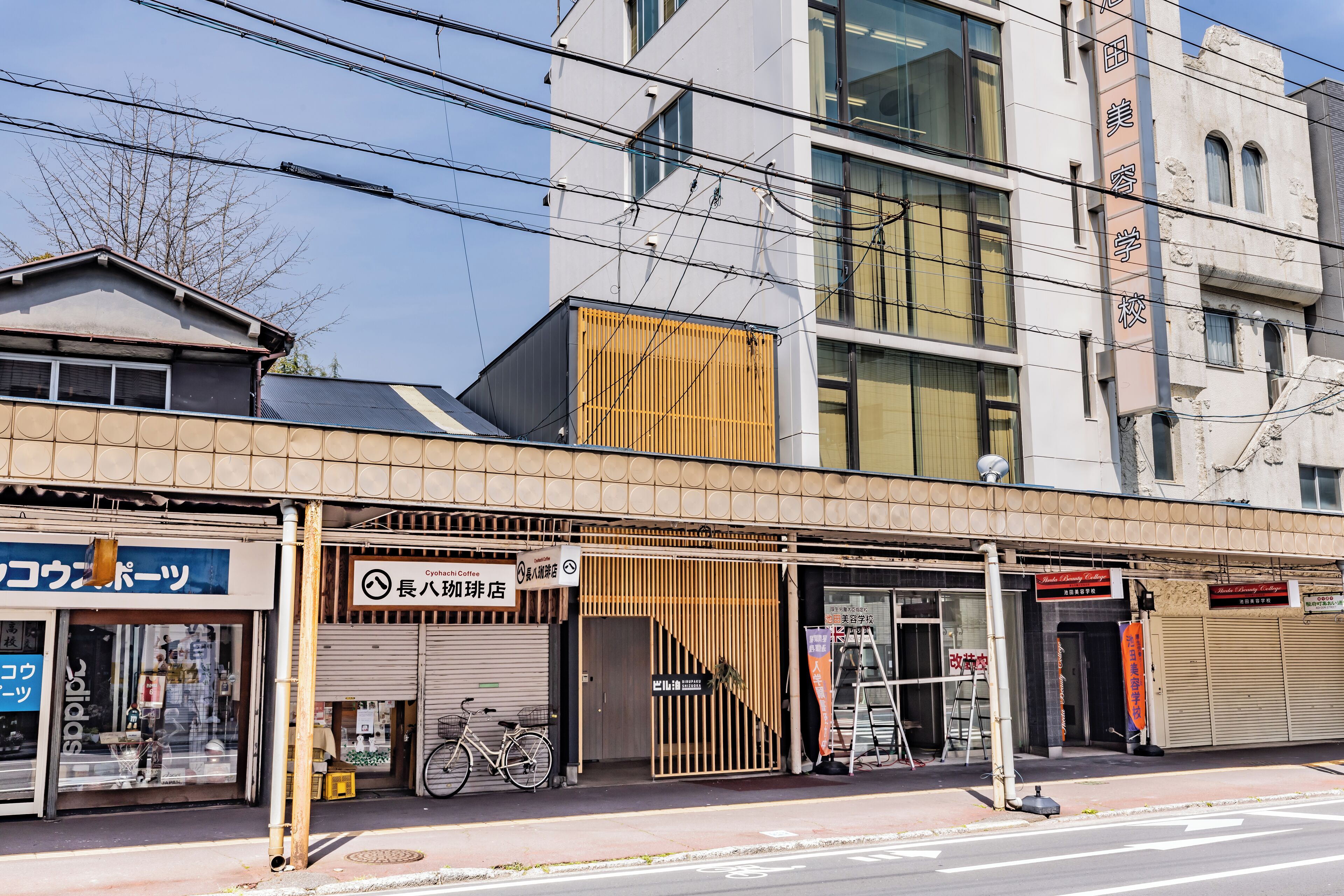 Vista de la calle con un edificio que tiene un letrero de cafetería y una bicicleta estacionada afuera.